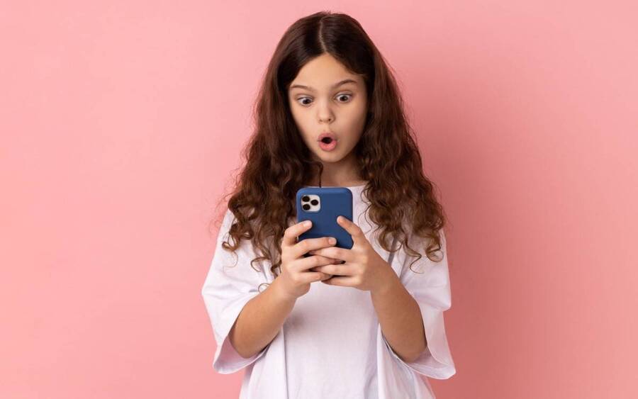 A girl looks at her smartphone with surprise.