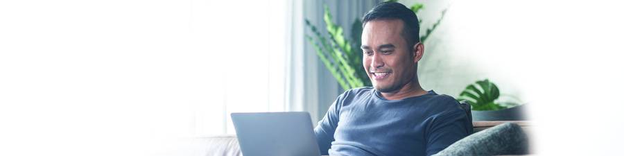 A man looks at his laptop, representing use of an online symptom checker through Scripps virtual care.