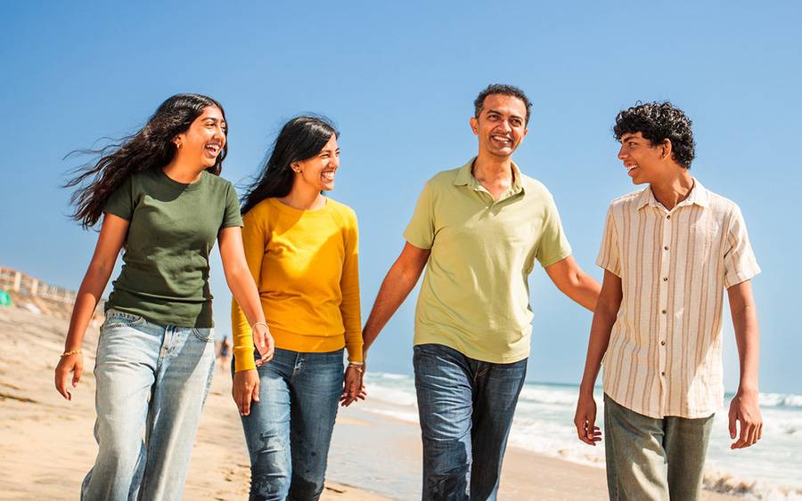 Abhi Adappa and his family laugh on the beach after Abhi, 46, recovering from surgery following a severe neck injury. 
