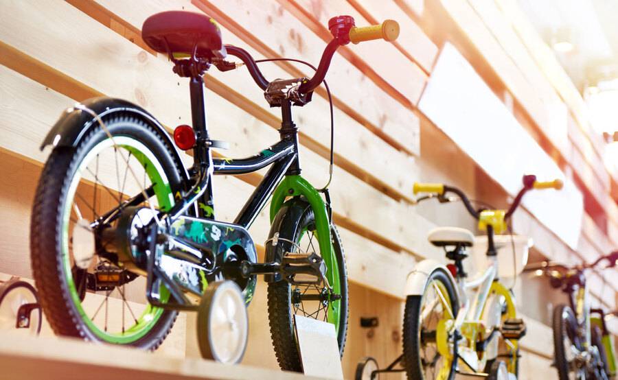 Three kids bicycles with training wheels on display in a store.