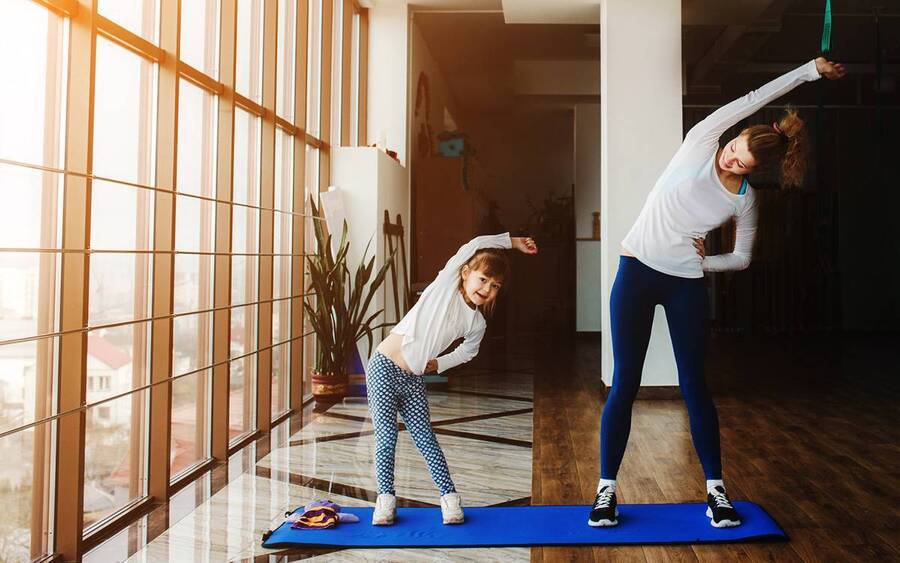 A mother and daughter exercising together, illustrating how to help promote physical fitness at home.