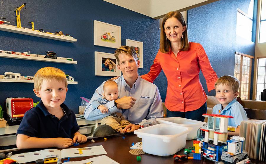 Richie Miller sits at a table filled with Lego pieces next to his three young sons, while wife Laura stands next to them.