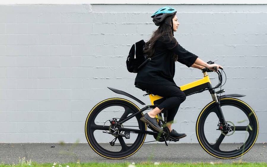 A young woman rides an e-bike on a bike path.