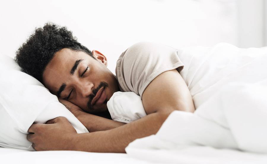 A young black man sleeps peacefully in a clean, comfortable environment.