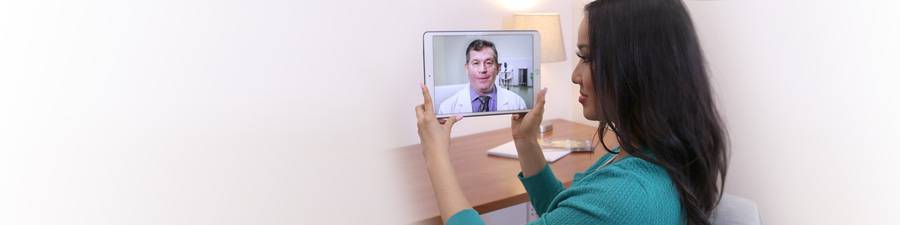 A woman holds a tablet device and talks to her doctor through Scripps virtual care.