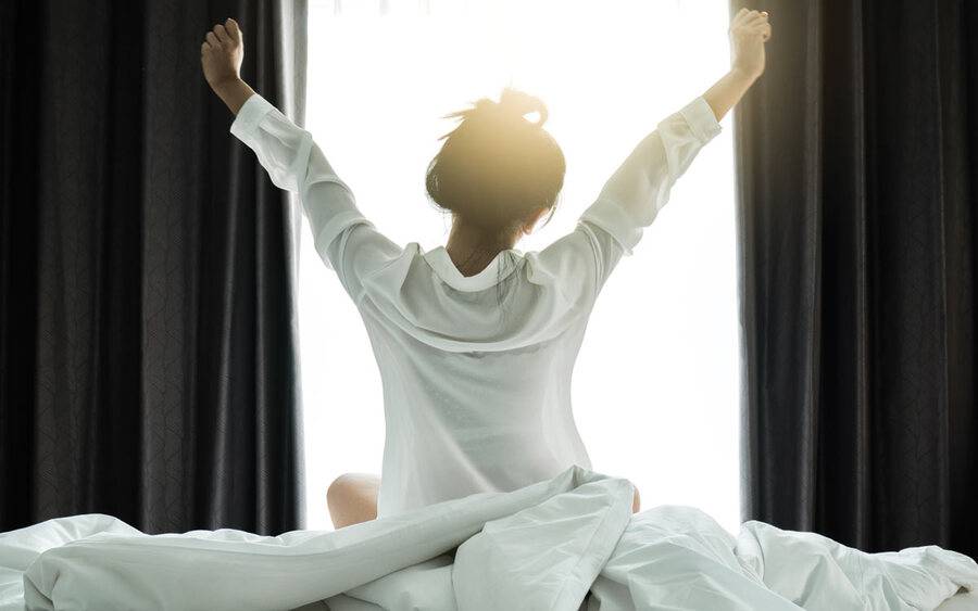 A woman stretching in the morning after a good night's sleep.