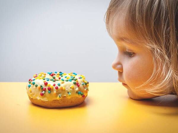 A young child staring at a donut