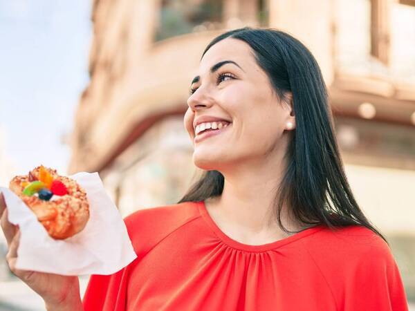 A woman in a red shirt holding a bagel