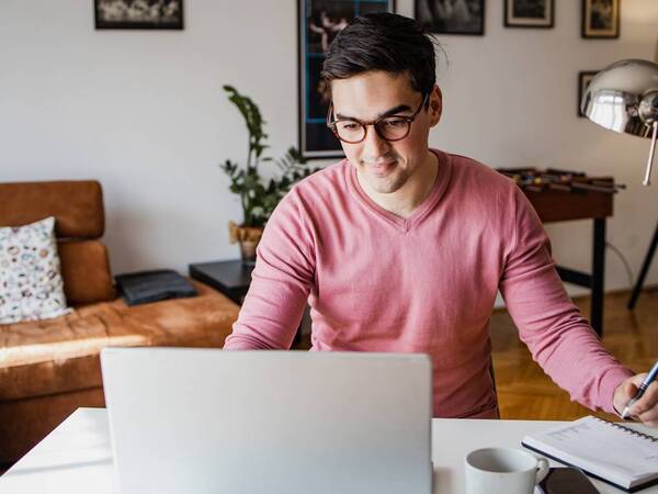 A young man in glasses looking at a laptop computer