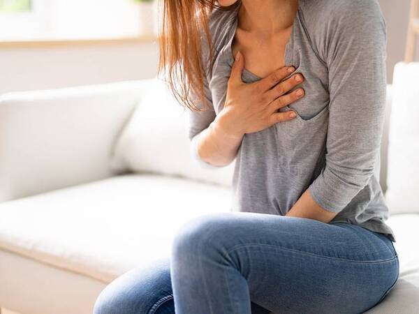 A woman grabs her chest, experiencing symptoms of atrial fibrillation, AFib.