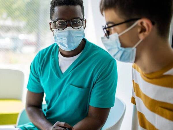 A young man talks to his doctor to be screened for testicular cancer.