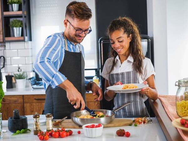 A young man and woman prepare a healthy meal in the kitchen.