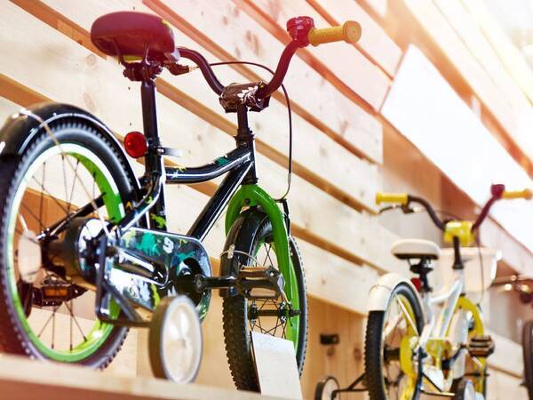 Three kids bicycles with training wheels on display in a store.