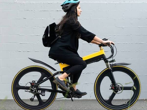 A young woman rides an e-bike on a bike path.