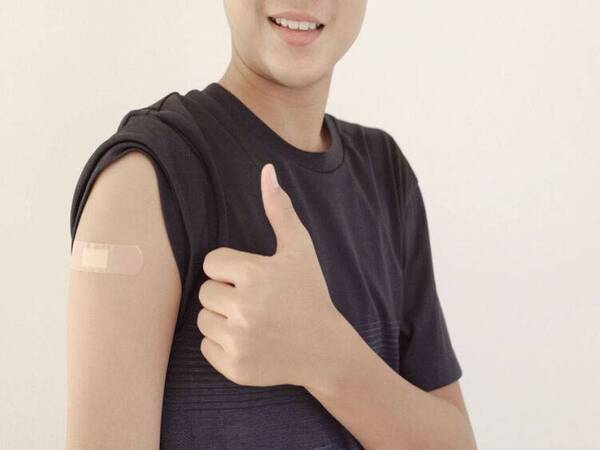 A youth shows his/her arm with a band aid in spot where they received HPV vaccine.